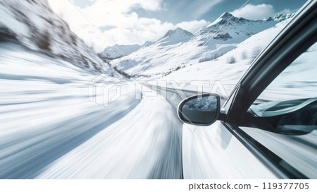 A car speeds along a snow-covered road surrounded by majestic mountains under a bright blue sky, capturing the essence of winter travel and adventure in a remote, scenic location. 119377705