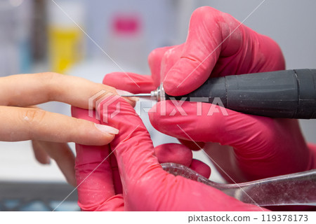Manicurist uses a nail drill to perfect a woman hardware manicure in a beauty salon Manicurist uses a nail drill to perfect a woman hardware manicure in a beauty salon 119378173