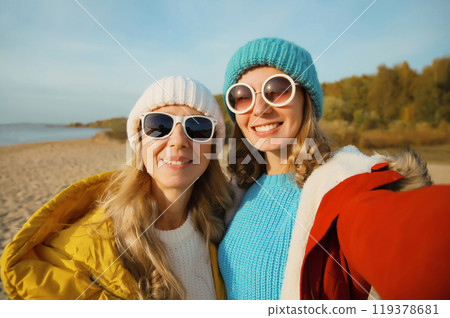 Happy young two women friends taking selfie with phone on beach, smiling girlfriends having fun Happy young two women friends taking selfie with phone on beach, smiling girlfriends having fun 119378681