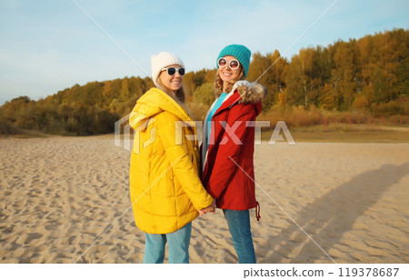 Happy young two women friends on sunny beach, stylish girlfriends smiles together on sea coast 119378687