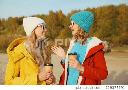 Happy two women friends talking on sunny beach, stylish girlfriends smiles together on sea coast Happy two women friends talking on sunny beach, stylish girlfriends smiles together on sea coast 119378691