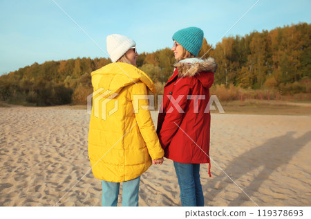Happy young two women friends on sunny beach, stylish girlfriends smiles together on sea coast 119378693