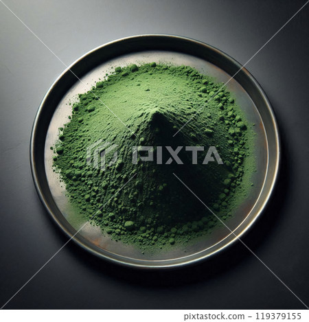 A mound of finely ground green powder sits on a metallic plate, creating a striking contrast against the dark background A mound of finely ground green powder sits on a metallic plate, creating a striking contrast against the dark background 119379155