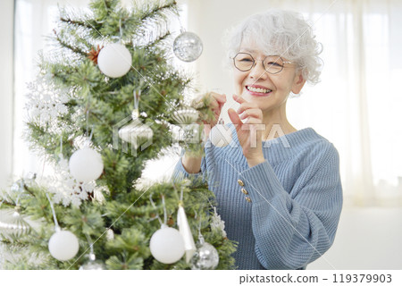 Senior woman decorating Christmas tree with ornaments Senior woman decorating Christmas tree with ornaments 119379903