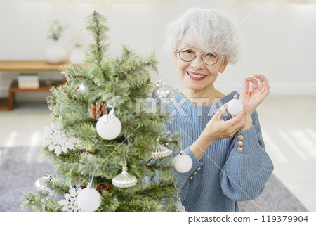 Senior woman decorating Christmas tree with ornaments 119379904