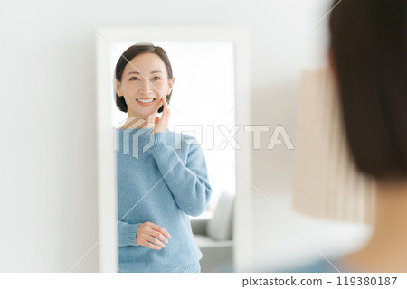 A woman in her 40s smiling in the mirror 119380187