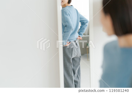 A woman looking in the mirror and getting ready A woman looking in the mirror and getting ready 119381240
