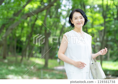 A middle-aged woman traveling in a tourist spot with fresh greenery 119381738