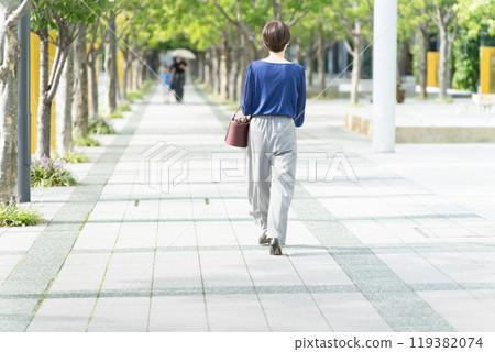 Woman walking along a tree-lined street 119382074