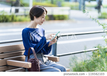 在戶外操作智慧型手機的年輕女子 119382103