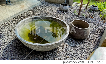 A round pond created from stones. Placed outdoor with some little stones under it. A round pond created from stones. Placed outdoor with some little stones under it. 119382215
