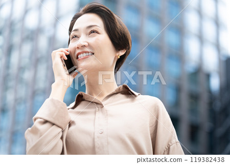 A woman making a phone call in a city A woman making a phone call in a city 119382438