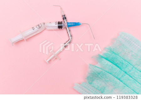 Broken Medical Syringe and Torn Medical Face Mask on the Pink Background Broken Medical Syringe and Torn Medical Face Mask on the Pink Background 119383328