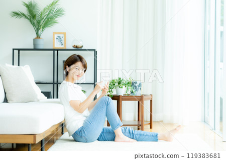 A woman who manipulates a smartphone in the living room A woman who manipulates a smartphone in the living room 119383681
