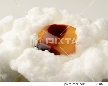 Pour soy sauce onto the egg yolk on top of the whipped egg white placed on rice. Pour soy sauce onto the egg yolk on top of the whipped egg white placed on rice. 119383825