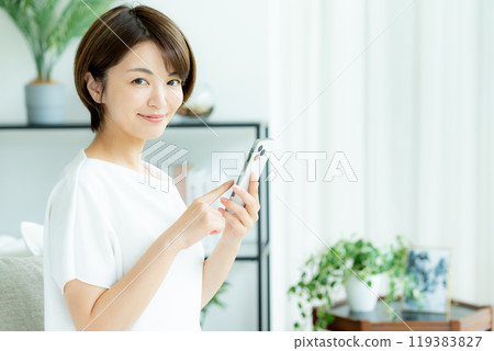 A woman who manipulates a smartphone in the living room A woman who manipulates a smartphone in the living room 119383827
