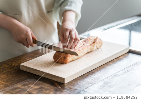 Woman's hands cutting French bread Woman's hands cutting French bread 119384252