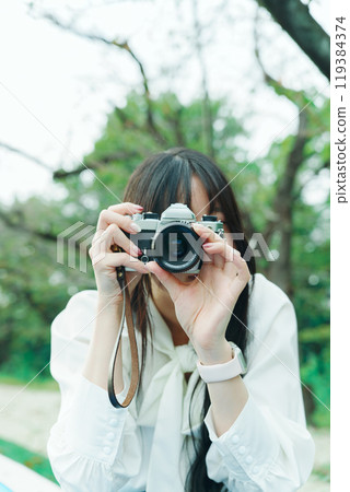 A woman looking through the viewfinder of a film camera A woman looking through the viewfinder of a film camera 119384374