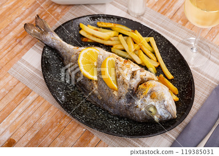 Whole baked dorado fish with potato on plate Whole baked dorado fish with potato on plate 119385031