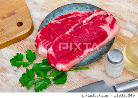 Slices of raw veal tenderloin on plate with greens Slices of raw veal tenderloin on plate with greens 119385049