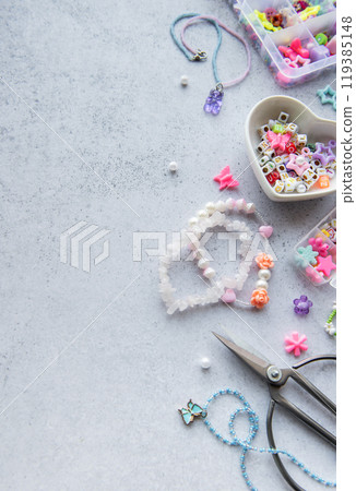 Colorful bead crafting materials arranged for creating unique jewelry pieces on a light grey surface 119385148