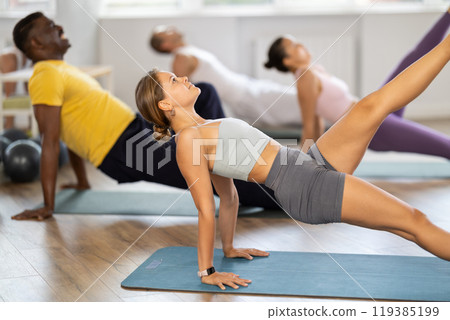 Girl performing one legged upward plank during group pilates training Girl performing one legged upward plank during group pilates training 119385199