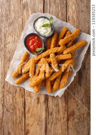 Breaded chicken fillet fries with dipping sauces close-up on parchment paper. Vertical top view 119385253