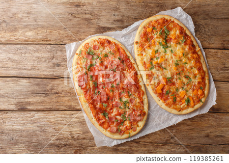 Homemade Pinsa Romana with Three cheeses, ham and tomato sauce close-up on parchment. Horizontal top view 119385261