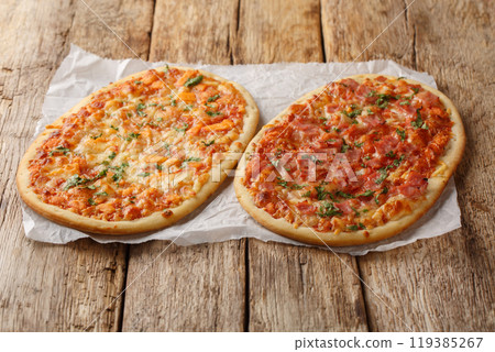 Pinsa Romana pizza with cheese, ham and tomato sauce close-up on parchment. Horizontal Pinsa Romana pizza with cheese, ham and tomato sauce close-up on parchment. Horizontal 119385267