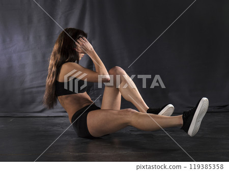 Beautiful athletic girl on a dark background Beautiful athletic girl on a dark background 119385358