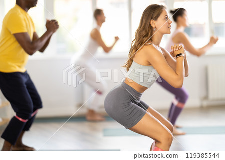 Girl using resistance loop during group pilates workout 119385544