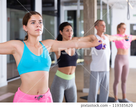 Sports people standing, perform various exercises, holding special small pilates balls in their hands Sports people standing, perform various exercises, holding special small pilates balls in their hands 119385620