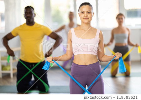 Asian woman doing resistance band exercises at group pilates session 119385621