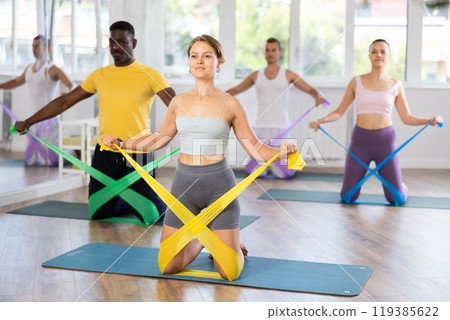 Fit girl exercising with resistance band in pilates class 119385622