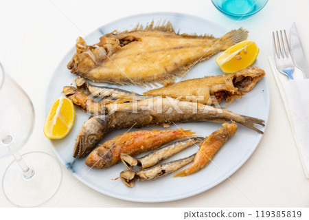 On white background, there is plate with fried fish of different varieties On white background, there is plate with fried fish of different varieties 119385819