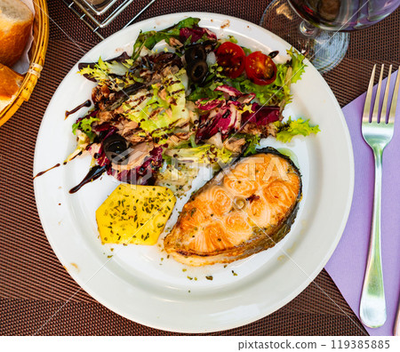 Salmon served with potatoes and vegetable salad 119385885