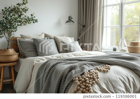 Minimalistic bedroom with bed, lamp and window. The bed is covered with a gray blanket and pillows 119386001