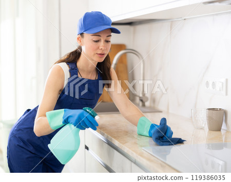 young positive girl is cleaning kitchen 119386035