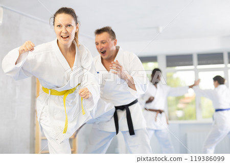 Woman and man in kimono and belts sparring during karate training 119386099