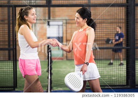 Young smiling women padel player handshaking Young smiling women padel player handshaking 119386305