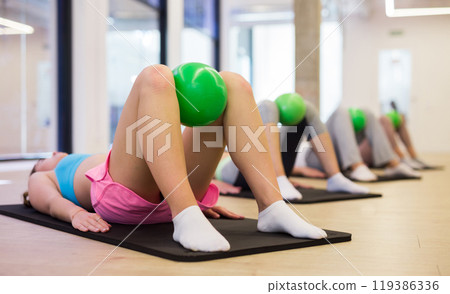 Group of people does a press exercise, performing a torso lift with a ball Group of people does a press exercise, performing a torso lift with a ball 119386336