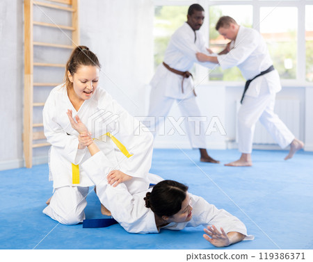 Adult and young women training judo techniques 119386371