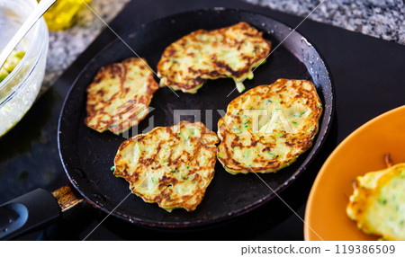 Cooking delicious zucchini pancakes in frying pan Cooking delicious zucchini pancakes in frying pan 119386509