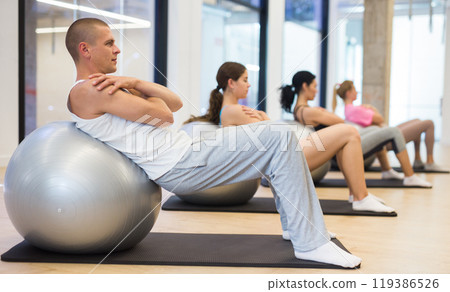 Focused man doing workout with pilates ball Focused man doing workout with pilates ball 119386526