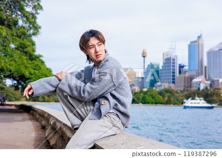 Japanese man sitting on the beach in Australia 119387296