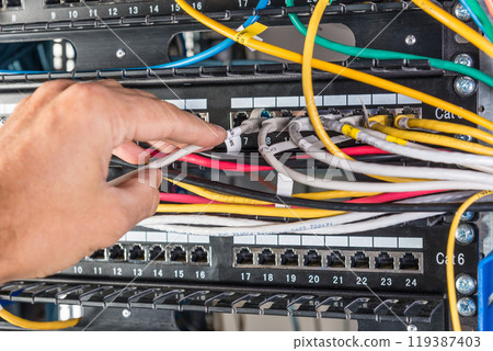 hand of engineer plugging in ethernet cable into server switch p 119387403