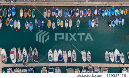 Aerial view of colorful boats docked in a marina, showcasing a vibrant array of vessels floating on clear blue waters. Nice, France Aerial view of colorful boats docked in a marina, showcasing a vibrant array of vessels floating on clear blue waters. Nice, France 119387456