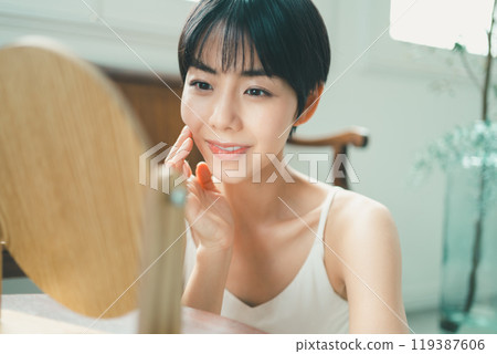 A woman doing skin care using a wooden tabletop mirror A woman doing skin care using a wooden tabletop mirror 119387606