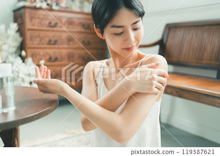 A young woman taking care of her body with body oil 119387621