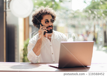Freelancer African Arabian business man working on laptop computer online in outdoors cafe 119388452